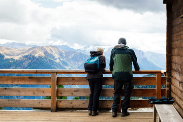 Happy family in sportswear with backpacks on the terrace admiring the Alps