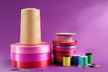 Many ribbons and sewing accessories on color background