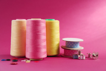 Many ribbons and sewing accessories on color background