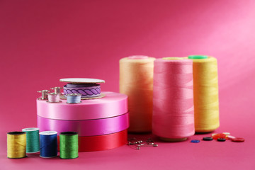 Many ribbons and sewing accessories on color background
