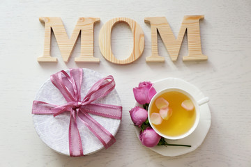 Mom word with cup of tea and flowers on wooden background. Mother Day concept