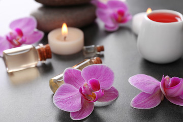 Fototapeta na wymiar Beautiful spa set with massage oil and orchid on the table, close up