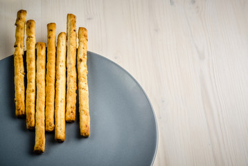 rustic breadsticks in a dish on wood table, close up, background