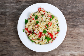 Homemade Fresh Couscous salad with vegetables, in white plate.