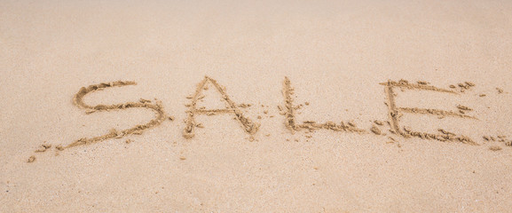 Summer sale handwritten in sand on a beach