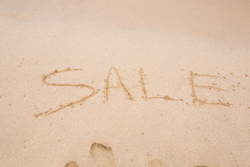 Summer sale handwritten in sand on a beach