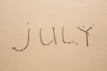 July - written in sand on beach texture, months year series