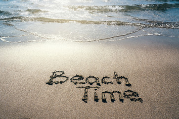 Beach time handwritten lettering on sand. Water sea background.