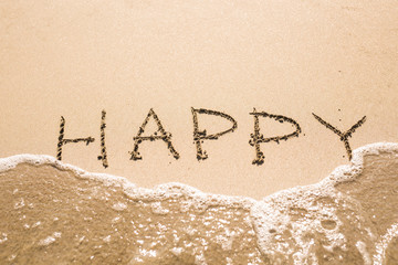 written words Happy on sand of beach