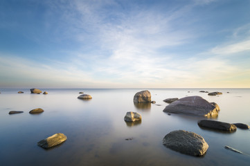 sea landscape, boulders in the water,sunset and colorful sky, slow shutter speed