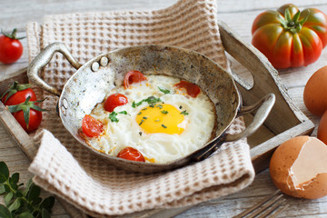 Fried egg with tomatoes and herbs n a old frying pan