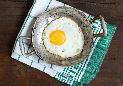 Fried egg in a old frying pan on napkin