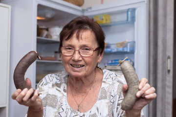 Happy senior woman holding pork liver sausages