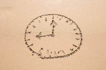 Time concept - Picture of a clock face on sandy beach.