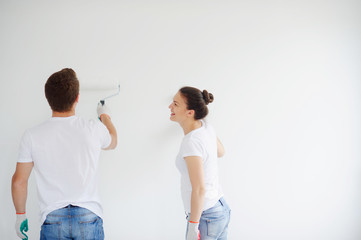 The guy and the girl paint a wall.