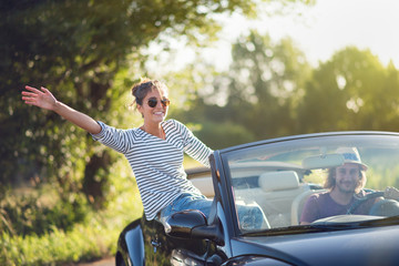 Young couple in his convertible car. Happiness and travel. - obrazy, fototapety, plakaty