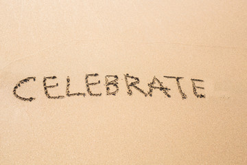 Fototapeta na wymiar celebrate word handwritten on a sand of beach