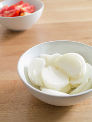 sliced onions in white bowl on wooden table