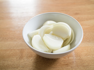 sliced onions in white bowl on wooden table