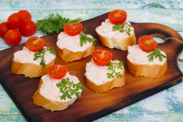 Canapes with cheese, tomatoes and herbs on a wooden background. Sandwiches