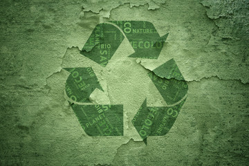 Abstract grunge creative green color recycle symbol on cracked and damaged background. Recycle symbol with added conceptual tags or words cloud that containing words related to ecology, etc.