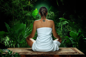 View of nice young woman meditating in spa environment