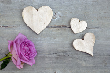 Pink purple rose on a grey old wooden background with white wash heart shape tags with empty copy space
