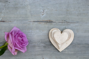 Fototapeta premium Pink purple rose on a grey old wooden background with white wash heart shape tags with empty copy space 