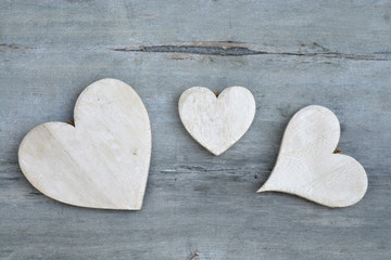 Three white wash hearts hand made of wood on a old grey wooden background with empty copy space
