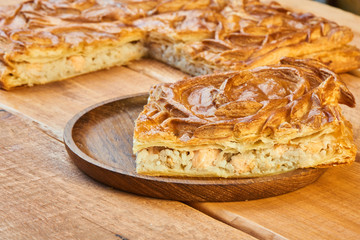 A piece of flaky fish pie with rice in wooden plate