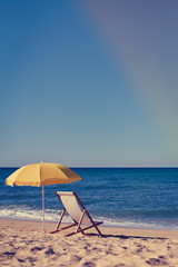 Back View Of Deckchair, Sun Lounger Under Umbrella On Sand Beach. 