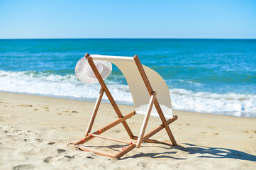 Deckchair and female hat on stunning tropical beach vacation background