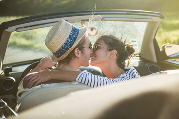 Rear view. A young couple kissing in a convertible car