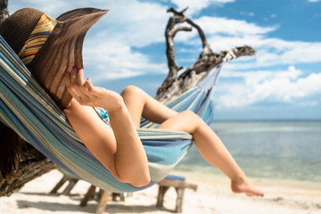 Frau im Urlaub am Strand entspannt in Hängematte am Meer