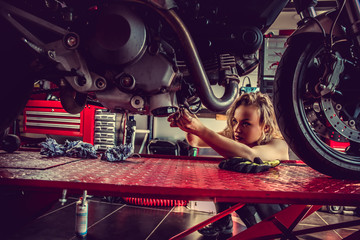 Obraz na płótnie Canvas Blond woman repairing motorcycle.