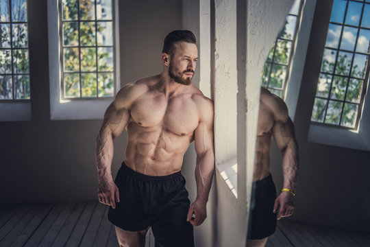 Shirtless bodybuilder posing in natural light.