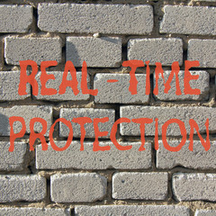 Real-time protection/ red inscription real-time protection against a background of white brick wall 