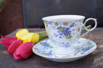 Tea cup, tulip flower, on wooden background