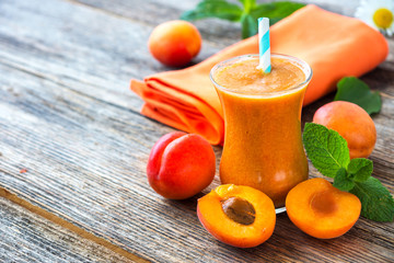 Fresh apricot smoothie and apricots on wooden  background