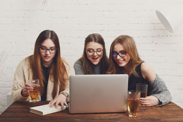 Portrait of three laughing girlfriends with laptop.