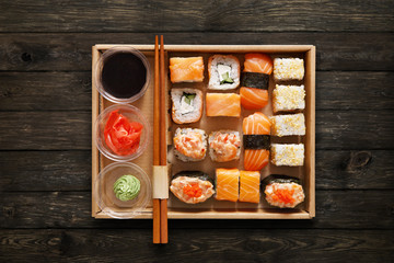 Set of sushi maki and rolls at box on wood.