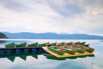 Blue lake with Rental rowing boats in marina. Wharf for trip ships.