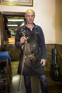Luthier showing a violin in his shop