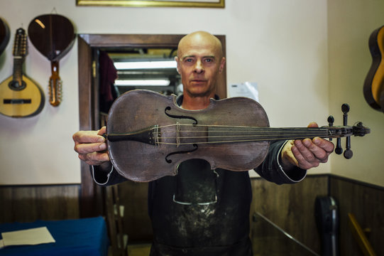 Luthier showing a violin in his shop