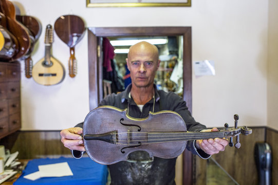 Luthier showing a violin in his shop