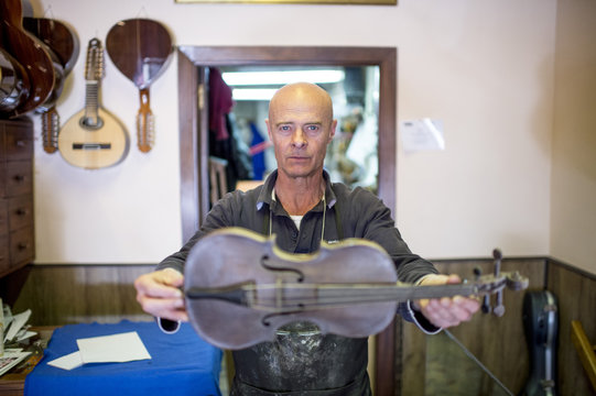 Luthier showing a violin in his shop