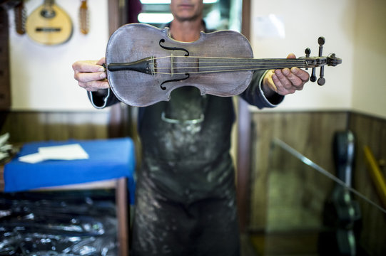 Luthier showing a violin in his shop