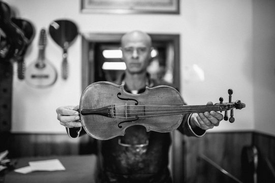 Luthier showing a violin in his workshop