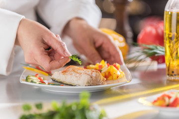 Hands of a chef putting the finishing touches on his fish dish