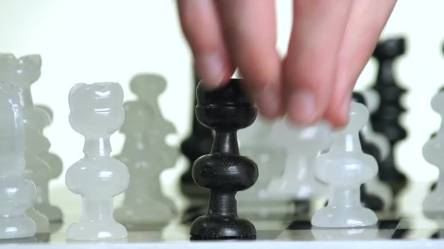 Male hand moving glass chess pieces on board